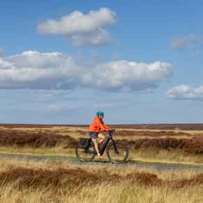 Cyclist riding in open moorland on a cycling holiday in England
